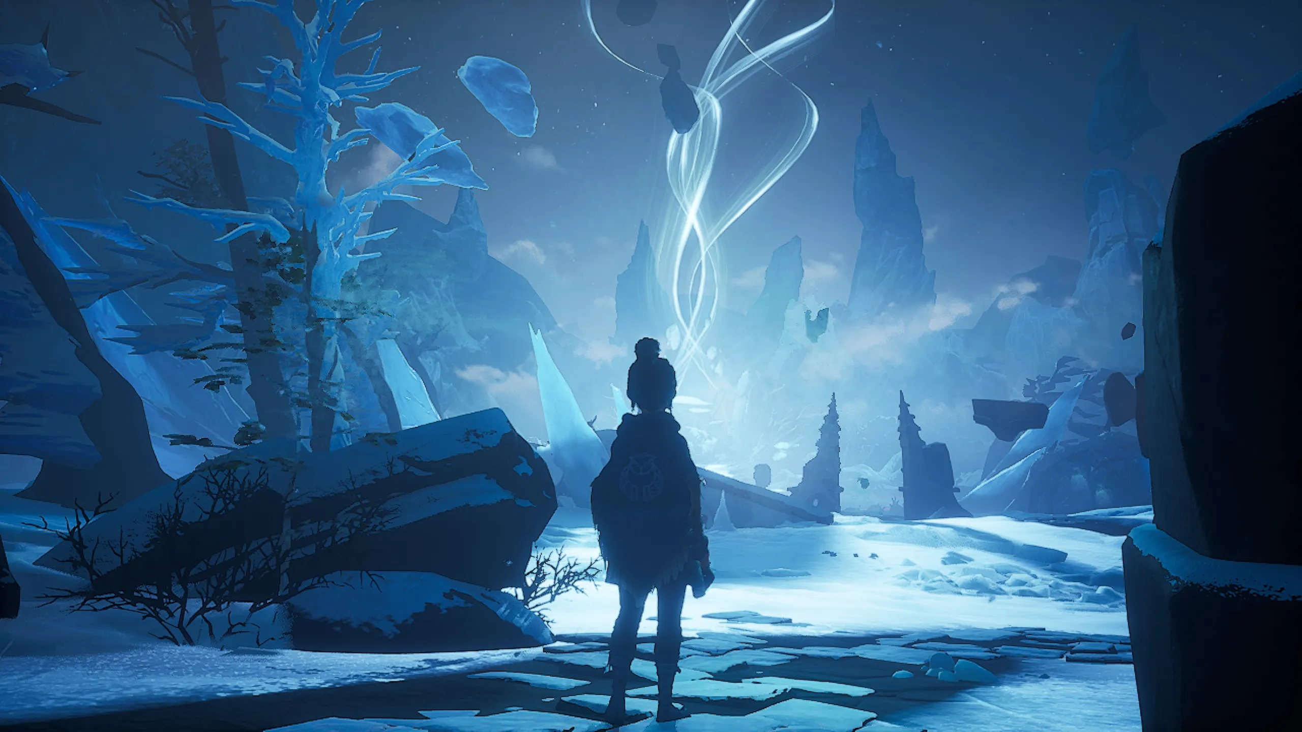 In-game screenshot from Kena: Bridge of Spirits showing Kena silhouetted against a sweeping blue-toned winter landscape. She stands facing a glowing white spirit trail spiraling into a star-filled sky above jagged ice formations, floating rocks, and snow-covered ruins, evoking a sense of wonder and discovery.