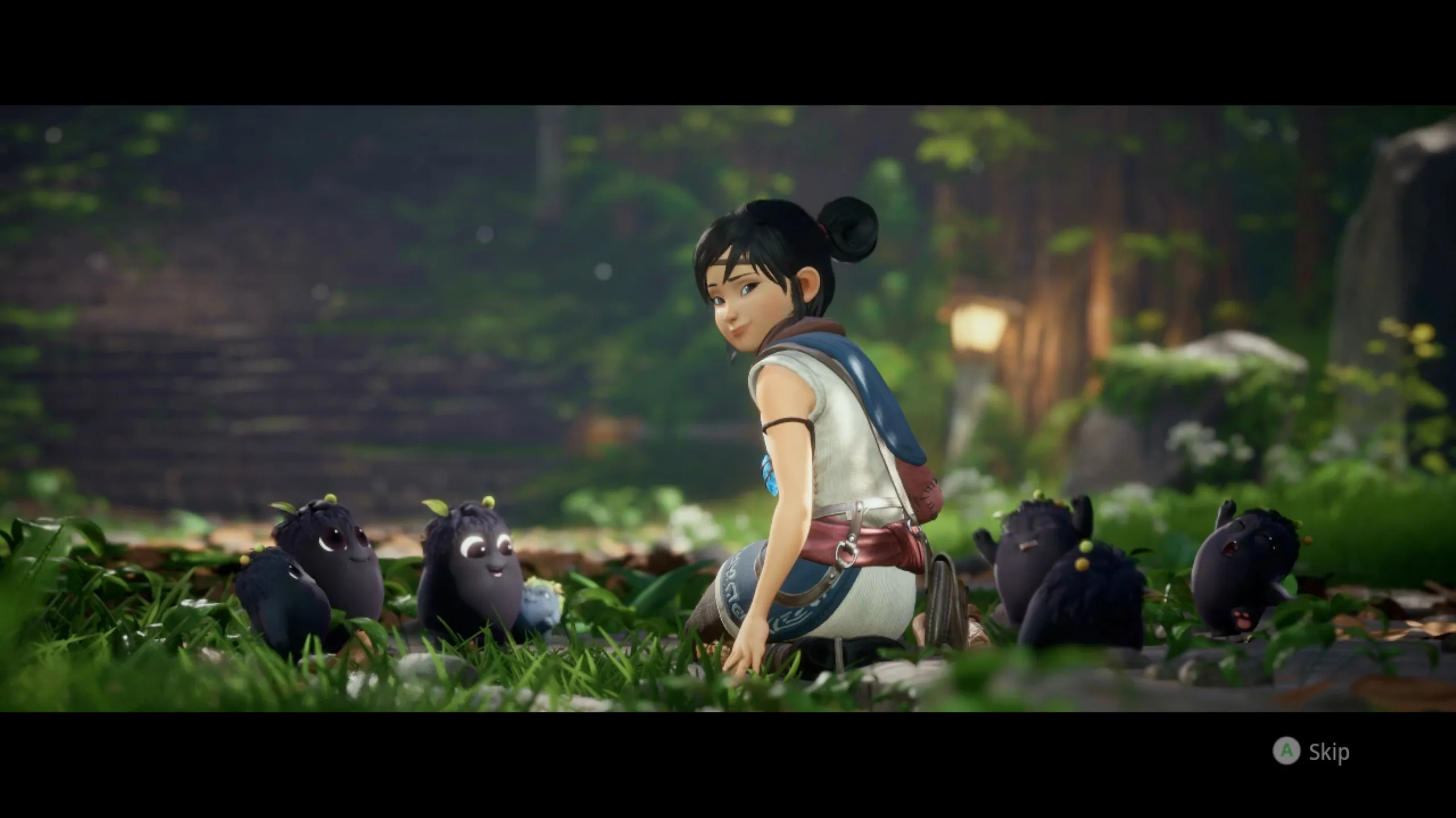A cinematic cutscene from Kena: Bridge of Spirits showing Kena crouching in a lush green forest setting, looking back over her shoulder with a gentle smile. She is surrounded by several small, round black Rot creatures with large expressive eyes, some wearing tiny leaf sprouts. The warm, Pixar-quality lighting and vibrant greenery give the scene a charming, heartfelt tone. A “Skip” prompt is visible in the bottom-right corner.