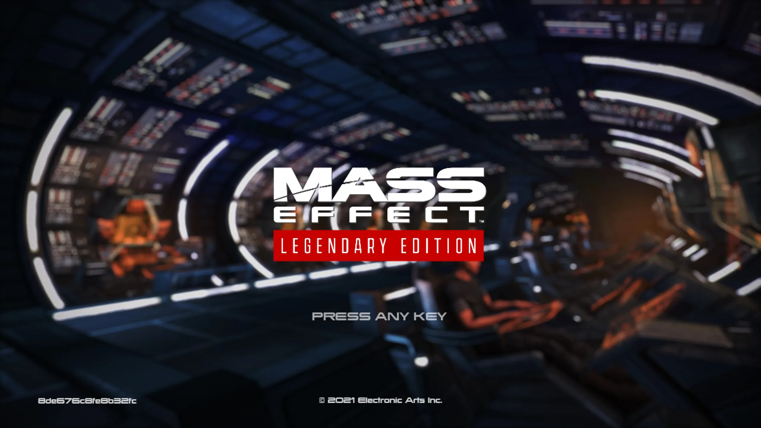 Mass Effect Legendary Edition title screen with white text over a blurred spaceship interior showing the Normandy’s cockpit with crew members visible in the background