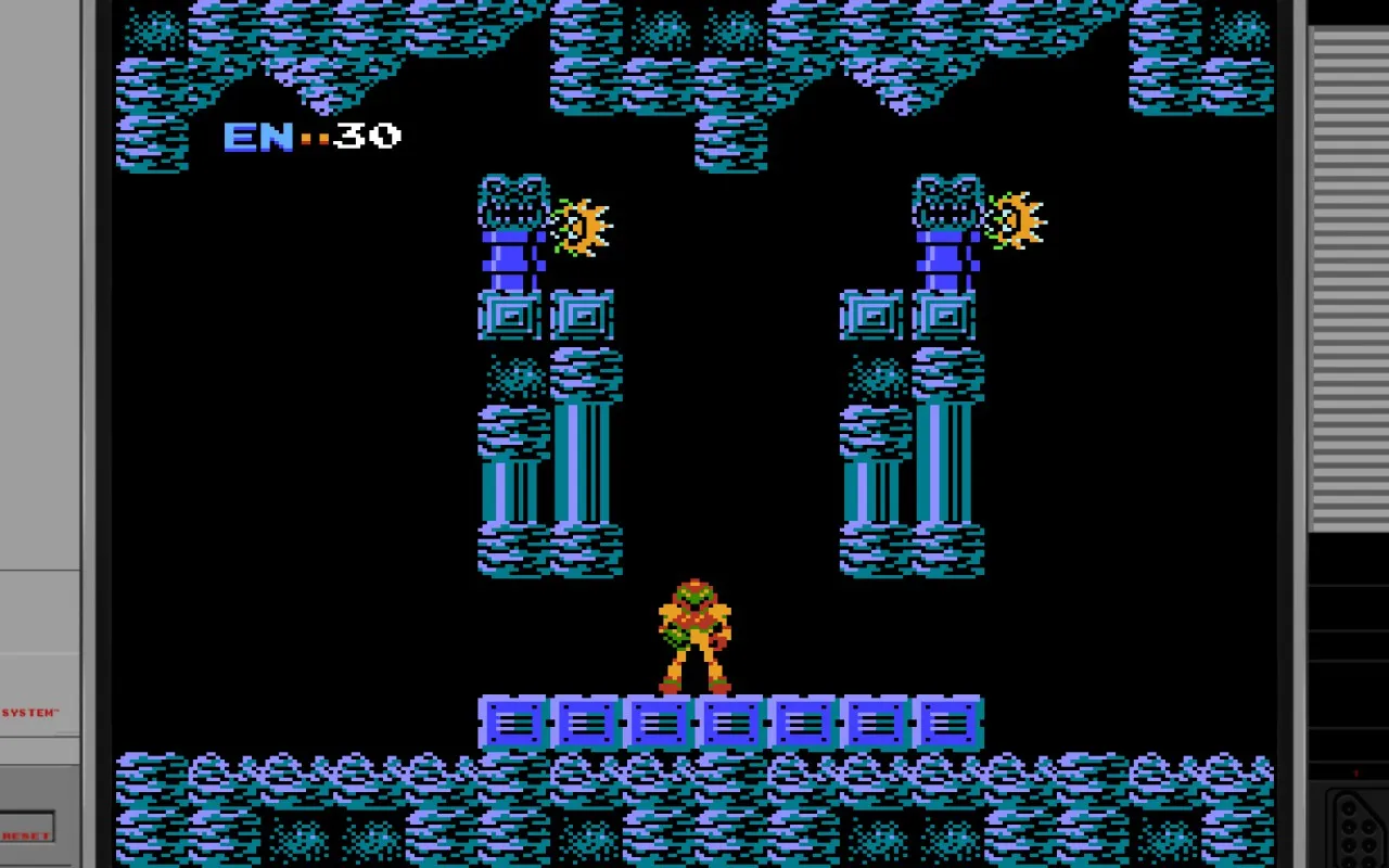 A Metroid NES gameplay screenshot showing Samus in her orange power suit standing in a dark underground chamber. The room features blue-tinted stone architecture with ornate columns and decorative ceiling details. Energy tanks are visible as blue rectangular objects, and there are glowing yellow enemies crawling the columns. The UI displays “ENERGY” with “30” remaining in the upper left corner.