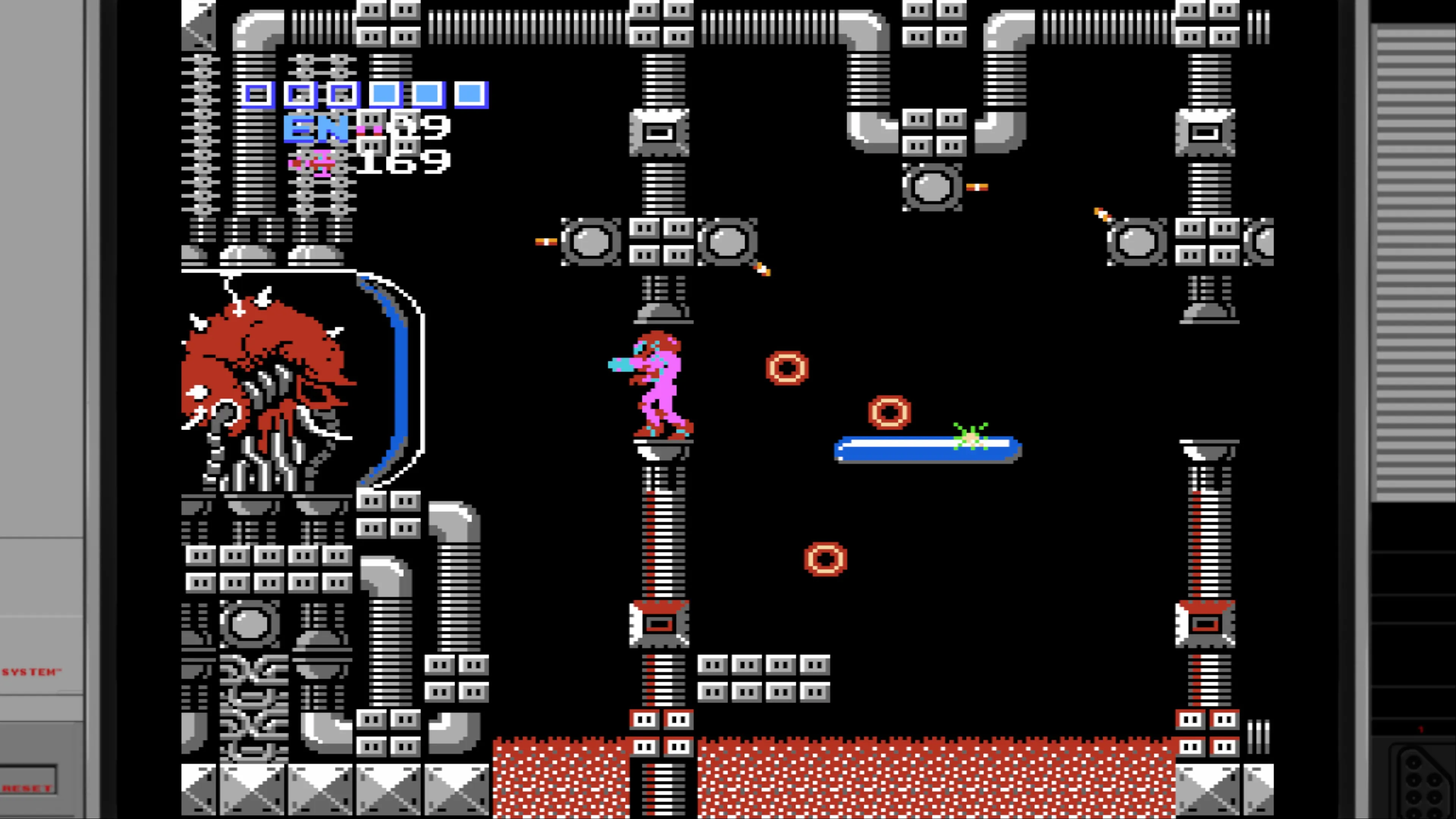 A Metroid NES screenshot depicting Samus in her pink suit navigating a complex mechanical area filled with gray industrial structures, pipes, and platforms. The scene includes multiple enemy projectiles (red circular objects) and what appears to be a blue platform. On the left side is a large mechanical structure with Mother Brain enemy visible. The UI shows energy tanks, missile count (169), and other status information in the upper left corner.