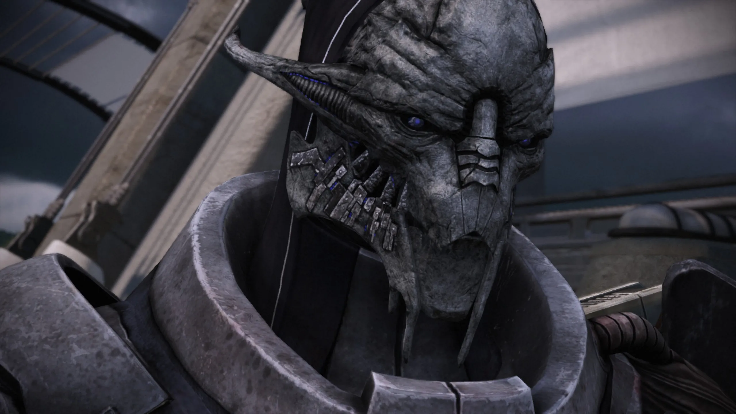 Close-up of Saren Arterius, a turian character with metallic gray skin, blue glowing eyes, and cybernetic implants on his face, shown in a menacing pose